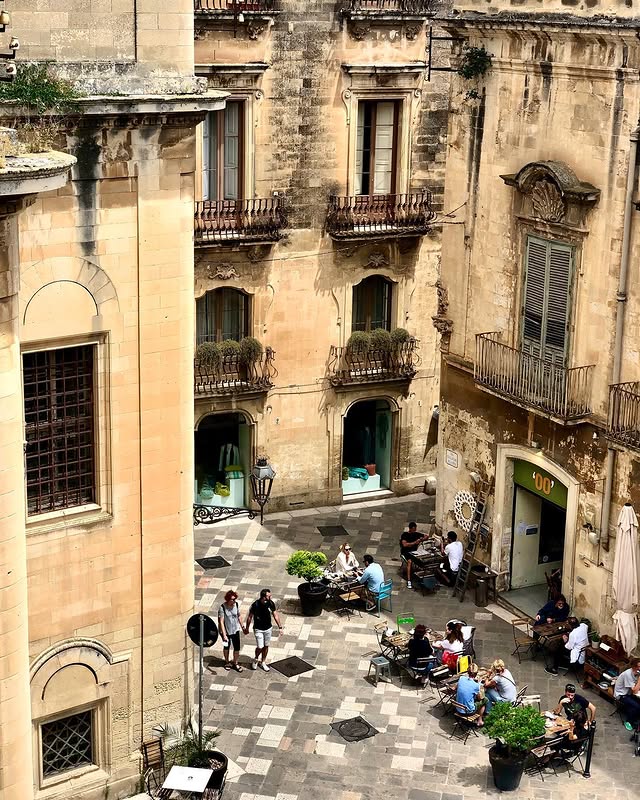 Plunging view of the terrace of the Doppiozero bar in Lecce, on  a piazza between old buildings