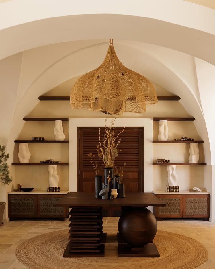 Focus on the hall of the boutique hotel tenuta negroamaro, with a design wooden table, rattan pendant and white sculpture on wooden shelves.
